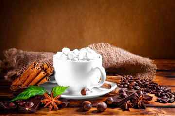 cup of hot chocolate, cinnamon sticks, nuts and chocolate on woo