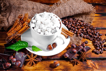 cup of hot chocolate, cinnamon sticks, nuts and chocolate on woo