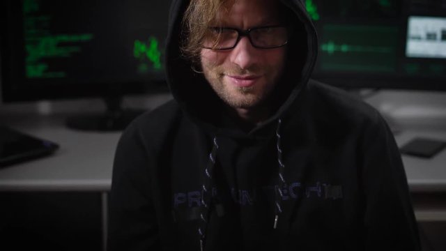 The man, dressed in gray trousers, a black jacket with a hood on his head, counts the money and then happily grins and winks. He looks like an evil genius or hackers, completes his hair