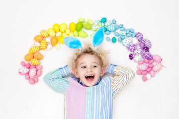 Obraz na płótnie Canvas Child on Easter egg hunt. Pastel rainbow eggs.