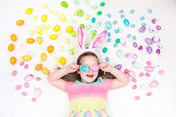 Child on Easter egg hunt. Pastel rainbow eggs.