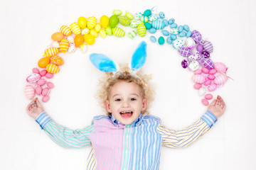 Child on Easter egg hunt. Pastel rainbow eggs.