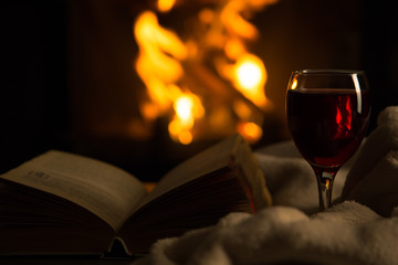 Open book with glass of wine in front of fireplace