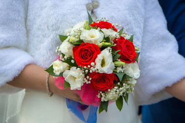 Wedding bouquet of red white flowers held by the bride