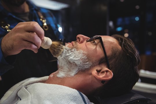 Mid section of barber applying cream on clients beard