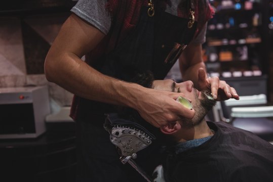 Mid section of Barber applying cream on clients beard