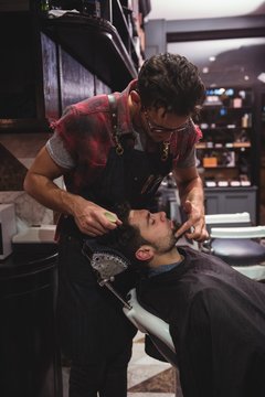 Barber applying cream on clients beard