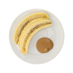 Ripe cut banana and a portion of peanut butter on a plate isolated on a white background. 