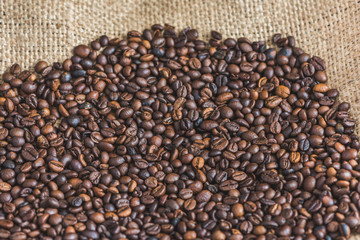 Heap of Roasted Coffee Beans on Burlap Background