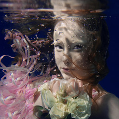 portrait of young beautiful red hair girl in pink dress and with roses underwater