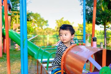 Young Asian boy play a iron train swinging at the playground und