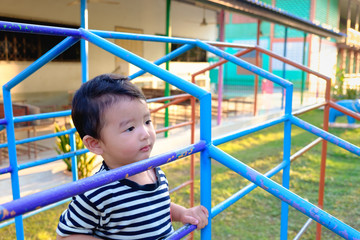 Asian boy hang the metal bar at outdoor playground.