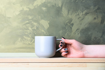 violet tea or coffee cup in hand on grey background
