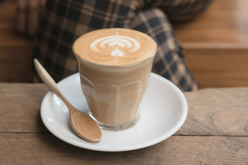 Hot glass of coffee on wooden table in the coffee shop.