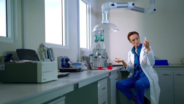 Female chemist working with liquid in chemistry lab. Chemical research. Chemistry woman pouring liquid in glass flask. Woman chemist in lab. Chemistry scientist scientist working at the laboratory