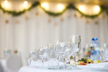 Glass cups and glasses and a plate of fish on a served table in a restaurant with a New Year's interior.