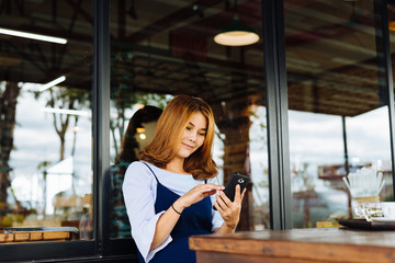 Woman using smart phone in a cafe,image of young woman sitting a