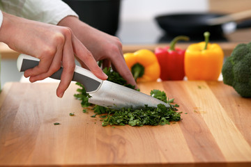 Closeup of human hands cooking vegetables salad in kitchen on the glass table with reflection. Healthy meal and vegetarian concept