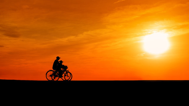 Image of sporty couple on bicycles outdoors against sunset. Silh
