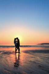Silhouettes of lovers on the beach with sunset