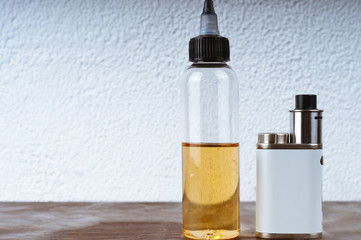 Electronic cigarette and a bottle of liquid on the table - 136639094