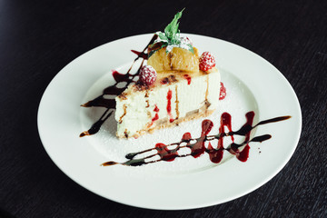 Philadelphia cake with raspberries and orange slice on white dish