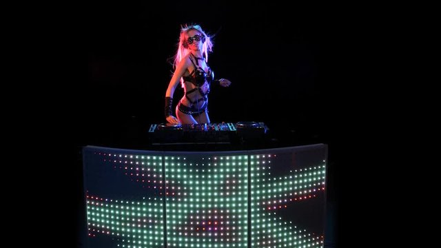 DJ blonde woman in neon light behind the decks