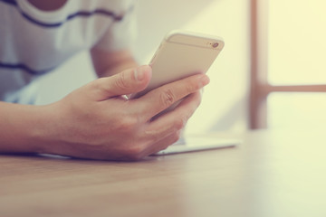 Close up man hand using smart phone for communicating with people or other:soft focus of boy hold mobile device for play:employee checking time schedule:user interface:vintage filter color effect.