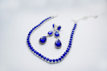 Blue necklace and earrings on white background at morning of bri