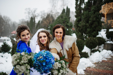 Bride and bridesmaids with bouquets on hands at winter wedding d