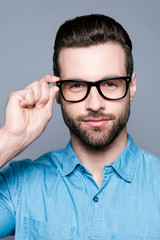 Obraz premium Portrait of handsome young serious man touching glasses
