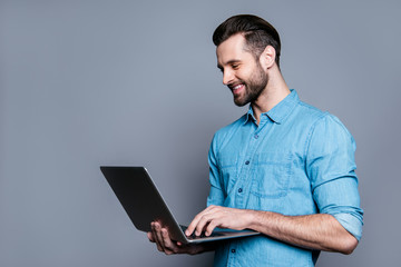 Smiling cheerful young man  holding laptop and typing