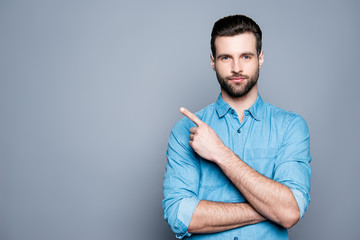 Handsome smiling bearded man pointing away on gray background