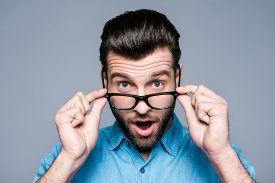 Wow! Surprised young man with opened mouth touching glasses