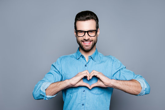 Portrait of happy handsome man in glasses making heart with fing