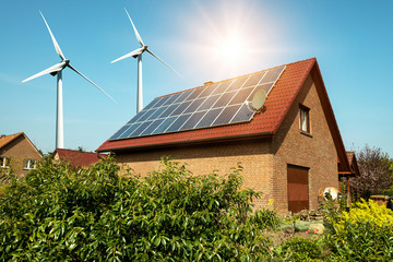 Solar panel on a roof of a house and wind turbins arround - concept of sustainable resources