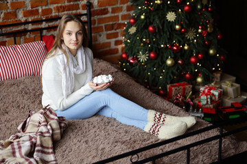 Christmas girl holding a marshmallow in hands, sitting on a bed