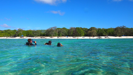 Fototapeta na wymiar Scuba divers surfacing near tropical island