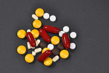 Tablets and pills on dark background. Lot of different pills on black background