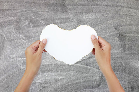 hands hold Burning paper heart on blackboard background