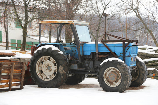 Blue old tractor on a farm in winter