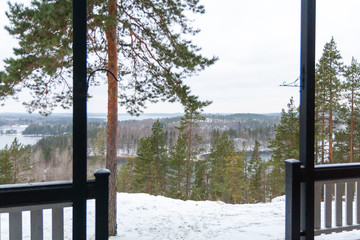 View of the winter forest lake in the hills from house porch.