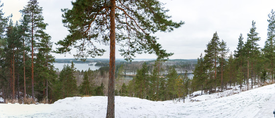 Panorama of the winter forest lake in the hills