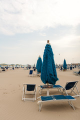 Deserted cold beach with umbrellas and sunbeds.