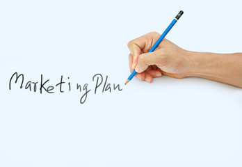 Hand holding a pencil on a white paper background, writing with pencil for word " Marketing Plan "