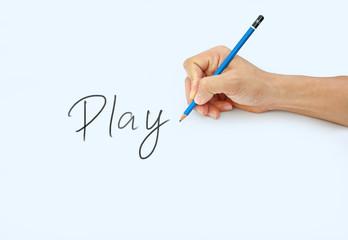 Hand holding a pencil on a white paper background, writing with pencil for word " Play"