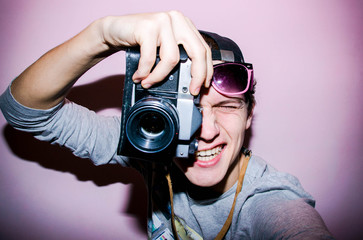 Portrait of the guy with retro camera on the bright background	