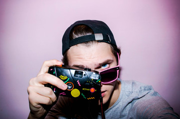 Portrait of the guy with retro camera on the bright background	