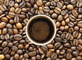 Top view of a paper cup of black brewed coffee on coffee beans texture