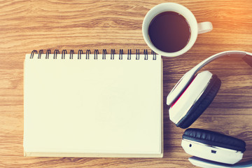 Blank notepad with headphone and coffee mug on table